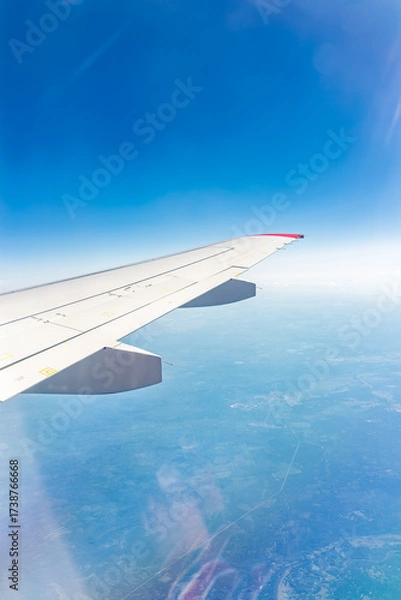 Fototapeta View from the airplane window at a beautiful blue clear sky and the airplane wing