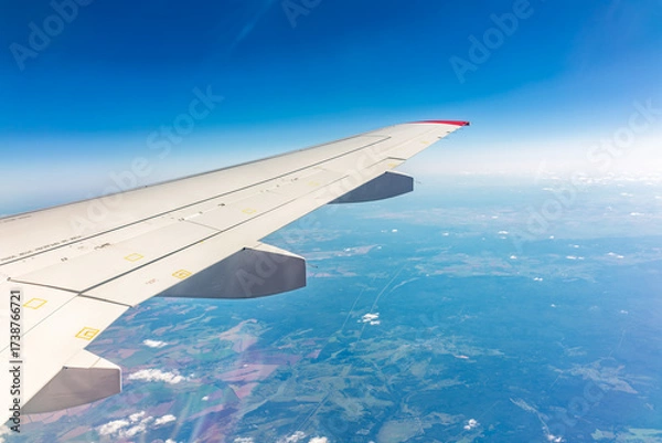 Fototapeta View from the airplane window at a beautiful blue clear sky and the airplane wing