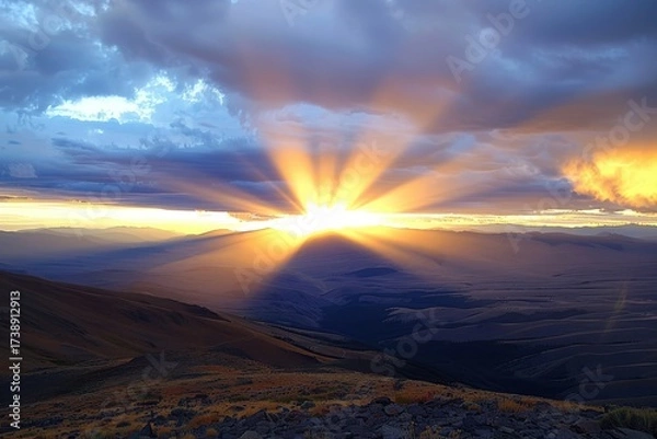 Fototapeta A breathtaking sunset casts rays of light over rolling hills and valleys, creating a stunning visual of nature's beauty.
