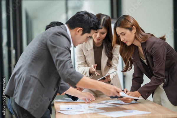 Fototapeta Group of businesspeople are standing in a meeting, exchanging knowledge in the office.
