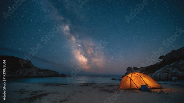 Fototapeta Camping under the night sky with a glowing tent and the Milky Way shining brightly above the beach