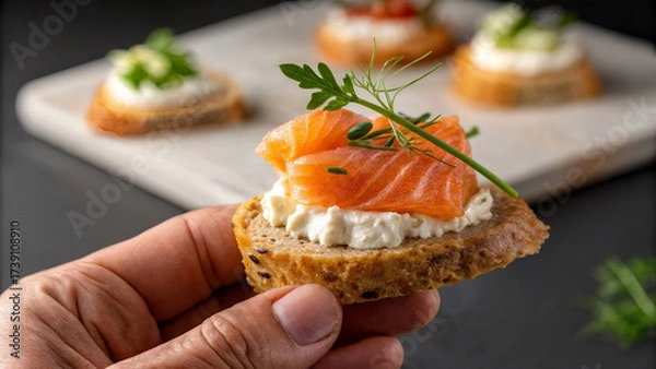 Fototapeta canapes with red fish and cucumber in hand