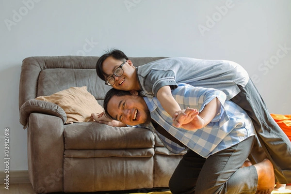 Fototapeta Happy Father and Son with Down Syndrome Playing Together at Home, Enjoying Quality Time and Laughter