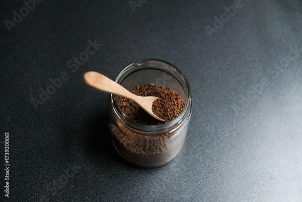 Fototapeta Instant coffee and spoon above glass jar on grey table, top view.