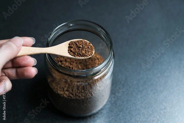 Fototapeta Instant coffee and spoon above glass jar on grey table, top view.