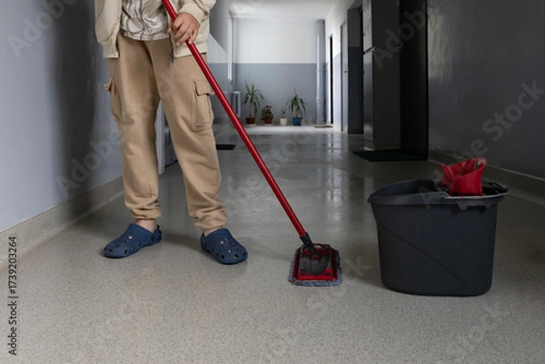 Fototapeta Person mopping a clean floor in a hallway with plants and bright walls during daylight hours