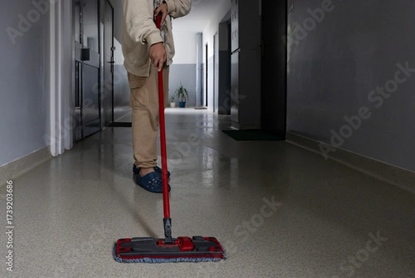 Fototapeta Person mopping a clean hallway in a modern building during daylight hours