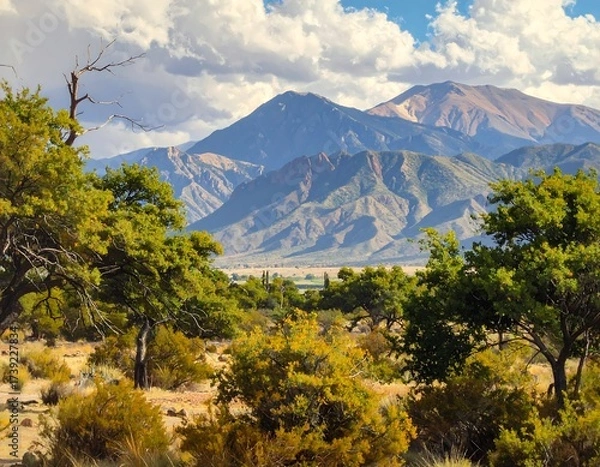 Fototapeta Stunning Landscape of Mountains, Trees, and Dramatic Clouds Under a Blue Sky