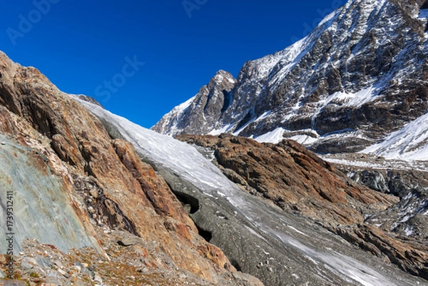 Fototapeta Glacier tongue flowing over rugged mountains. View of the anun and langgletscher in Loetschental valley in Valais, Switzerland