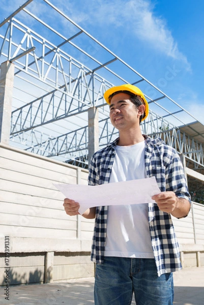 Fototapeta Building architect with plans overseeing construction site