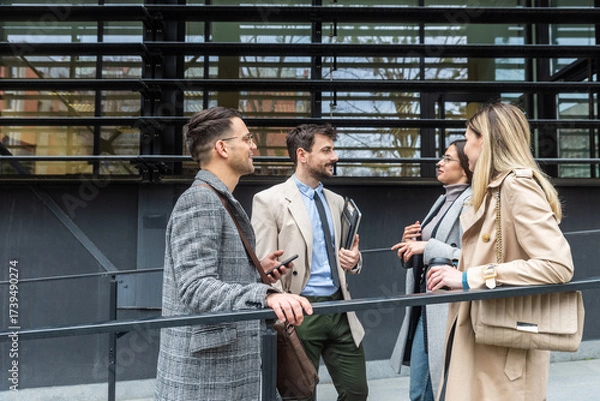 Fototapeta IT experts freelance workers innovative technology developers, working on a new project staff meeting with casual talk in formalwear outside office building before the work. Discussing business people