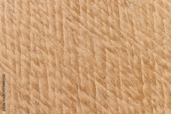 Fototapeta The sea and wind create soft textures in the sand on the beach, a backdrop for presentations.