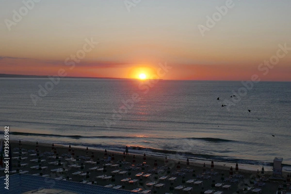 Fototapeta Beautiful early sunrise from the horizon on the sea , illuminated by the sun, which creates reflections orange and yellow shades on the surface of the water.