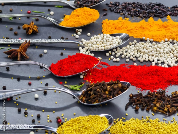 Fototapeta Colorful spices arranged on silver spoons showcasing a variety of flavors and textures in a kitchen setting