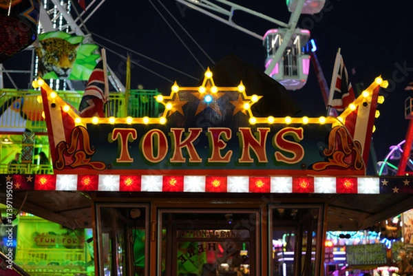 Obraz Illuminated tokens sign and Ferris wheel at the vibrant Goose Fair in Nottingham, England, on a festive evening.