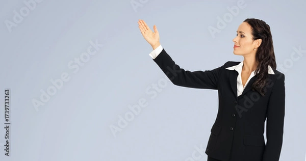 Fototapeta Profile portrait of smile cute businesswoman woman wear black corporate suit, pointing showing upward and looking same direction. Business concept. Isolated gray grey background with free text space