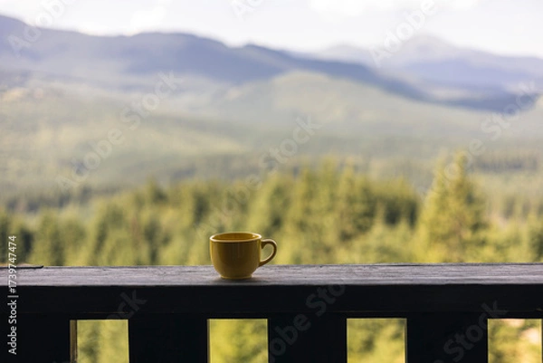 Fototapeta Yellow cup on balcony with mountain view and space for text or quote.