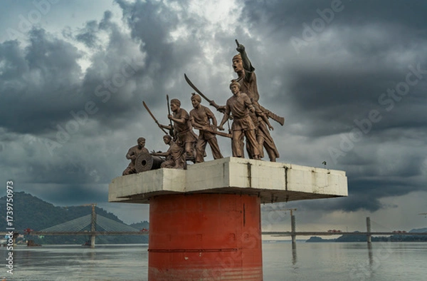 Fototapeta A statue of Lachit Borphukan stands in the Brahmaputra River under a cloudy sky