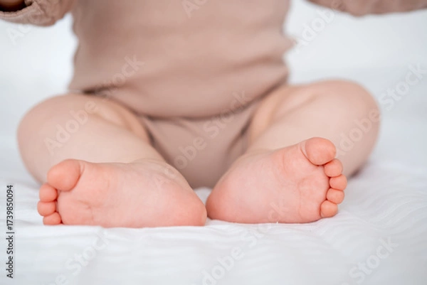 Obraz baby's legs on a white bed, a place for text
