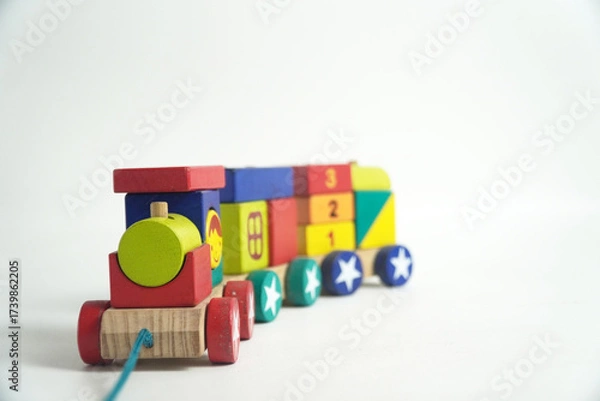 Fototapeta A colorful wooden toy train with blocks of different shapes and numbers, isolated against a white background. This image is perfect for concepts of childhood, learning, games, and vintage toys.

