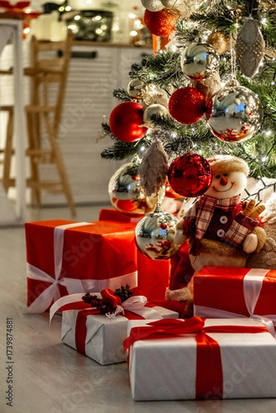 Obraz a Christmas tree with a New Year decor with red balls and gifts under it, a New Year's festive atmosphere at home