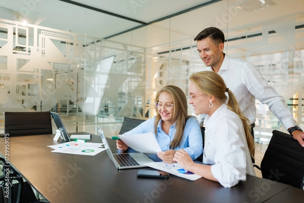 Fototapeta Team collaborating in modern office space to analyze business reports