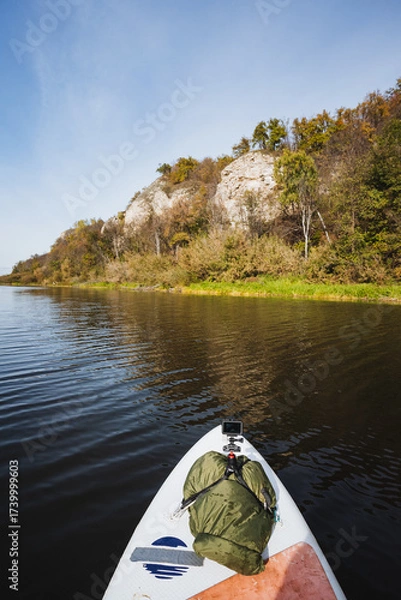 Fototapeta Enjoy paddleboarding on calm waters, amidst beautiful autumn cliffs. This serene experience connects you with nature, rejuvenating your spirit and offering a peaceful escape from daily stress