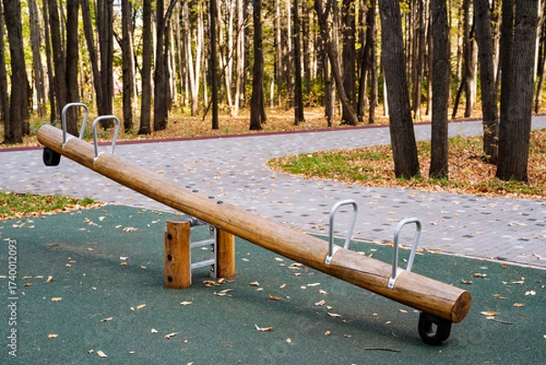 Fototapeta Explore the Outdoor Wooden SeeSaw Playground Equipment in a serene forest, designed for kids to improve balance, engage in teamwork, and have fun during exciting, educational playtime activities