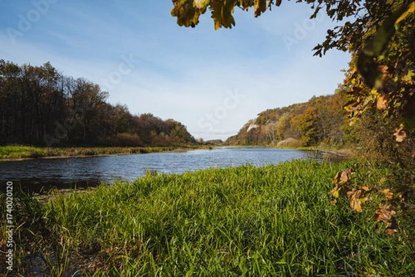 Fototapeta Serene River Landscape with Lush Greenery and Autumn Foliage