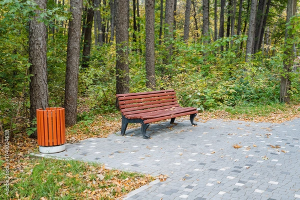 Fototapeta In a serene park, a charming bench in a vibrant forest invites visitors to relax and appreciate natures beauty, offering a peaceful escape for reflection amid the soothing sounds of wildlife