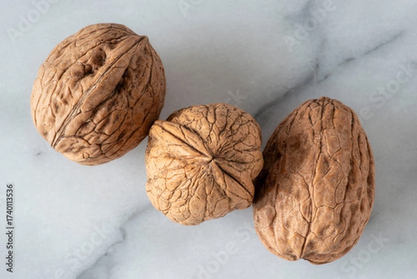 Fototapeta Close-up of walnuts in their shells on white marble