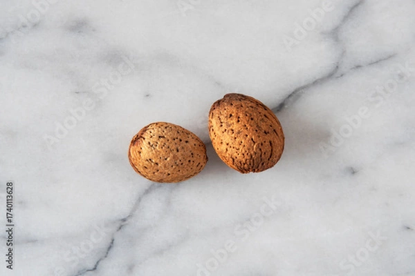 Fototapeta Close-up of almonds with their shells on white marble
