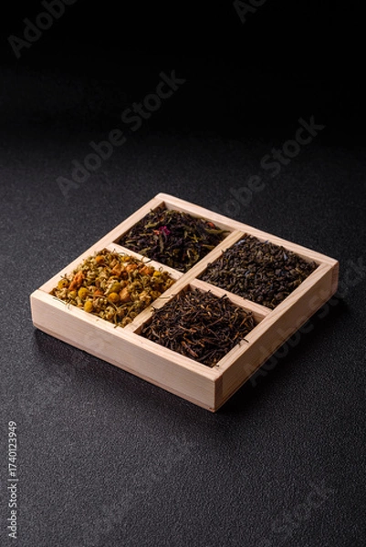 Fototapeta A wooden box with several types of dried tea, green, black, fruit, and chamomile. Dry tea in the box