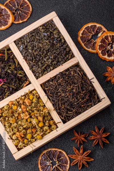 Fototapeta A wooden box with several types of dried tea, green, black, fruit, and chamomile. Dry tea in the box