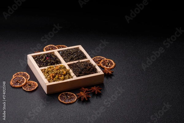 Fototapeta A wooden box with several types of dried tea, green, black, fruit, and chamomile. Dry tea in the box