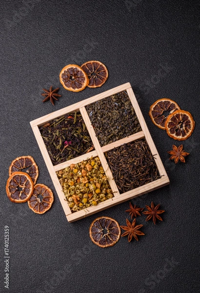 Fototapeta A wooden box with several types of dried tea, green, black, fruit, and chamomile. Dry tea in the box