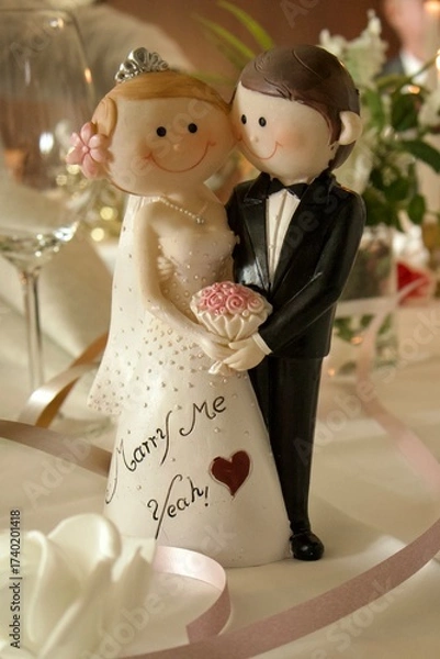 Fototapeta A figurine of bride and groom in wedding attire, used as decoration for a wedding table or cake, symbolizing love, joy, and union.