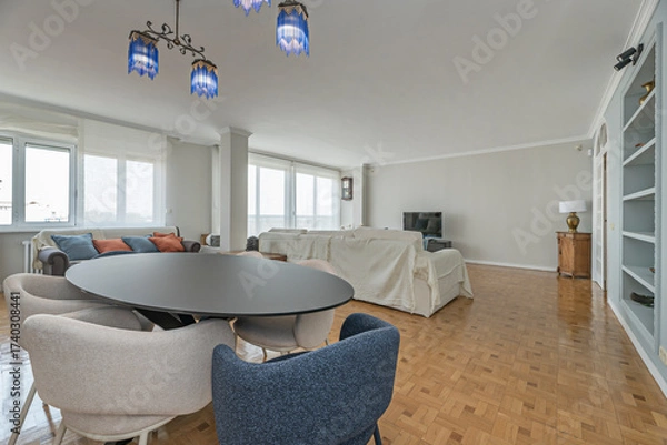 Fototapeta Family dining room with a large dark wood table and high-backed chairs upholstered in beige fabric, cozy and functional