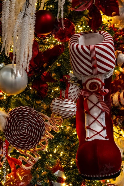 Fototapeta Christmas tree with sparkling garland lights and decorative red Santa Claus boot for gifts, selective focus