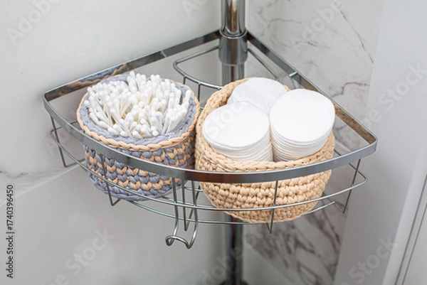 Fototapeta Stylish bathroom storage solution featuring woven baskets filled with cotton pads and swabs, elegantly arranged on a chrome shelf against a marble wall, enhancing organization and aesthetics