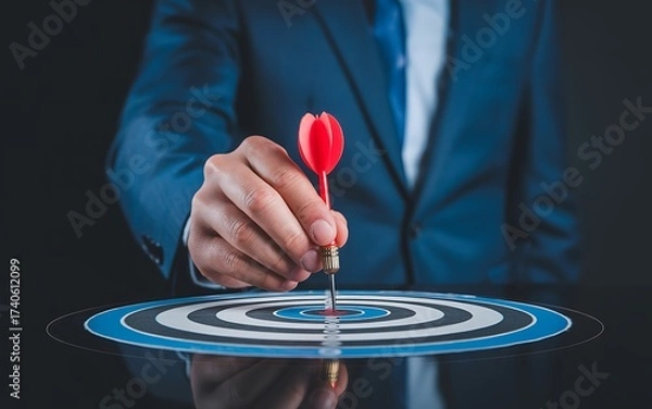 Fototapeta Businessman aiming dart at center of target board