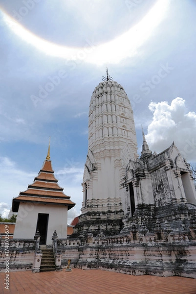 Fototapeta A white main prang in Khmer art and a Thai-style building, with a sun halo in the sky at Wat Phutthaisawan, Thailand.