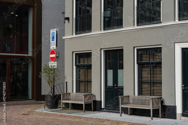 Fototapeta Urban gray building with benches and dark green doors and window frames on a sunny day in a city.