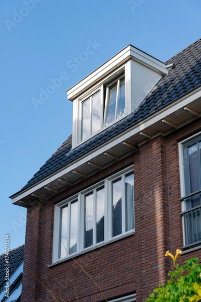 Fototapeta Exterior shot of a red brick home with a dormer window. Open window hints at the interior.