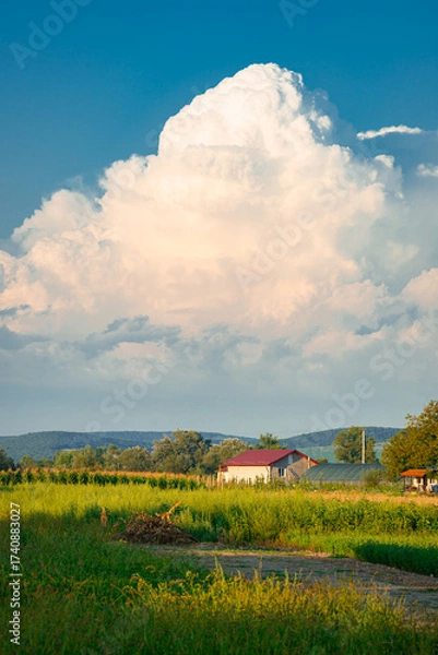 Fototapeta Large Cumulonimbus storm cloud over the foothills of the eastern Carpathian Mountains in Romania. Idyllic rural scene in the foreground.