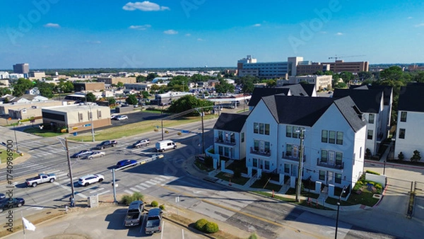 Fototapeta Cooper and Main Street intersection in downtown Arlington, Texas during peak hour. New development townhomes, retail buildings, and parking lots form a dense, transit-integrated urban corridor