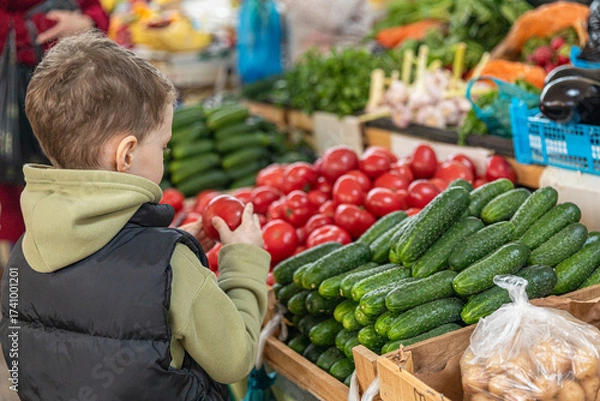 Fototapeta Rear view unrecognizable little boy son buying fresh cucumbers and tomatoes at farmer's market. Healthy nutrition concept. High quality photo