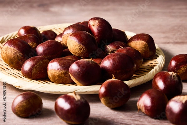 Obraz 籠に盛られた利平栗。日本の秋を代表する和栗で、濃厚な甘みとほくほくした食感が特徴。秋の味覚や季節感を表現する食材写真として、自然、収穫、健康、農産物、伝統的な食卓シーンなどにも利用可能。