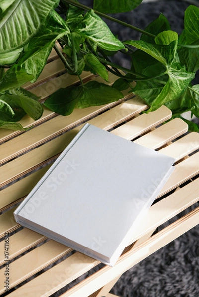 Fototapeta blank book mockup on decorative table with many green plants