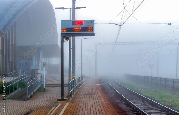 Obraz Rail train station in heavy fog in summer morning 